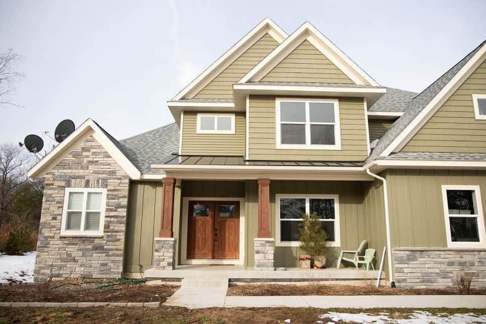 Modern house with green siding and stone accents, showcasing quality craftsmanship.