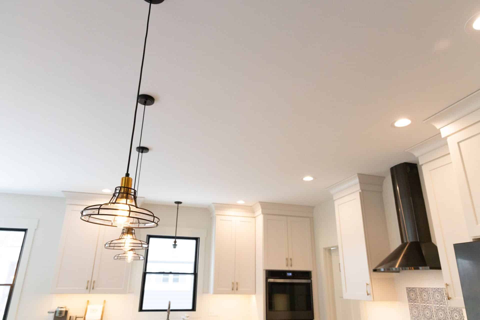 Modern kitchen with white cabinets, pendant lighting, and stainless steel appliances.