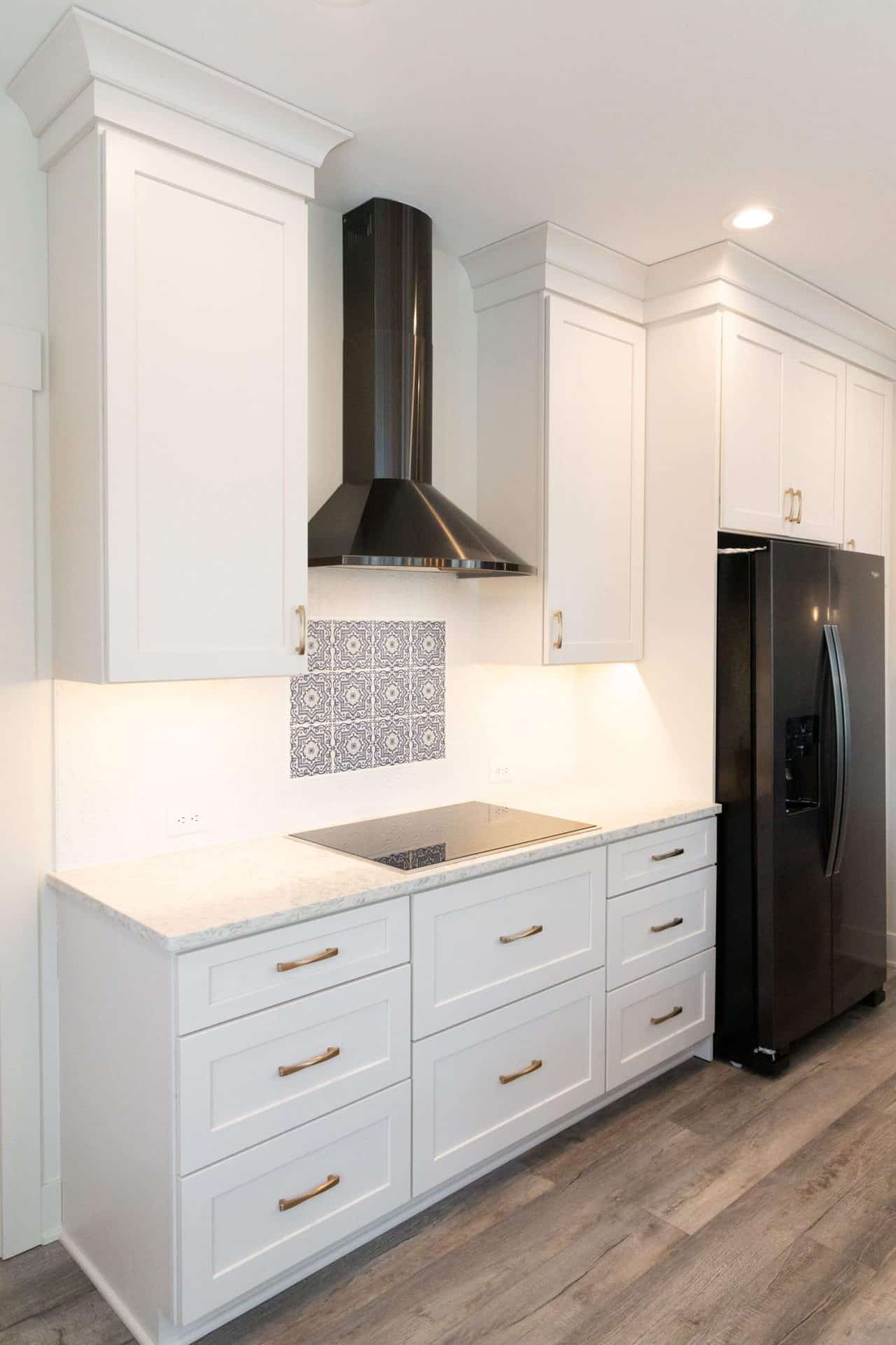 Contemporary kitchen featuring white cabinets, black refrigerator, and sleek range hood for a modern.
