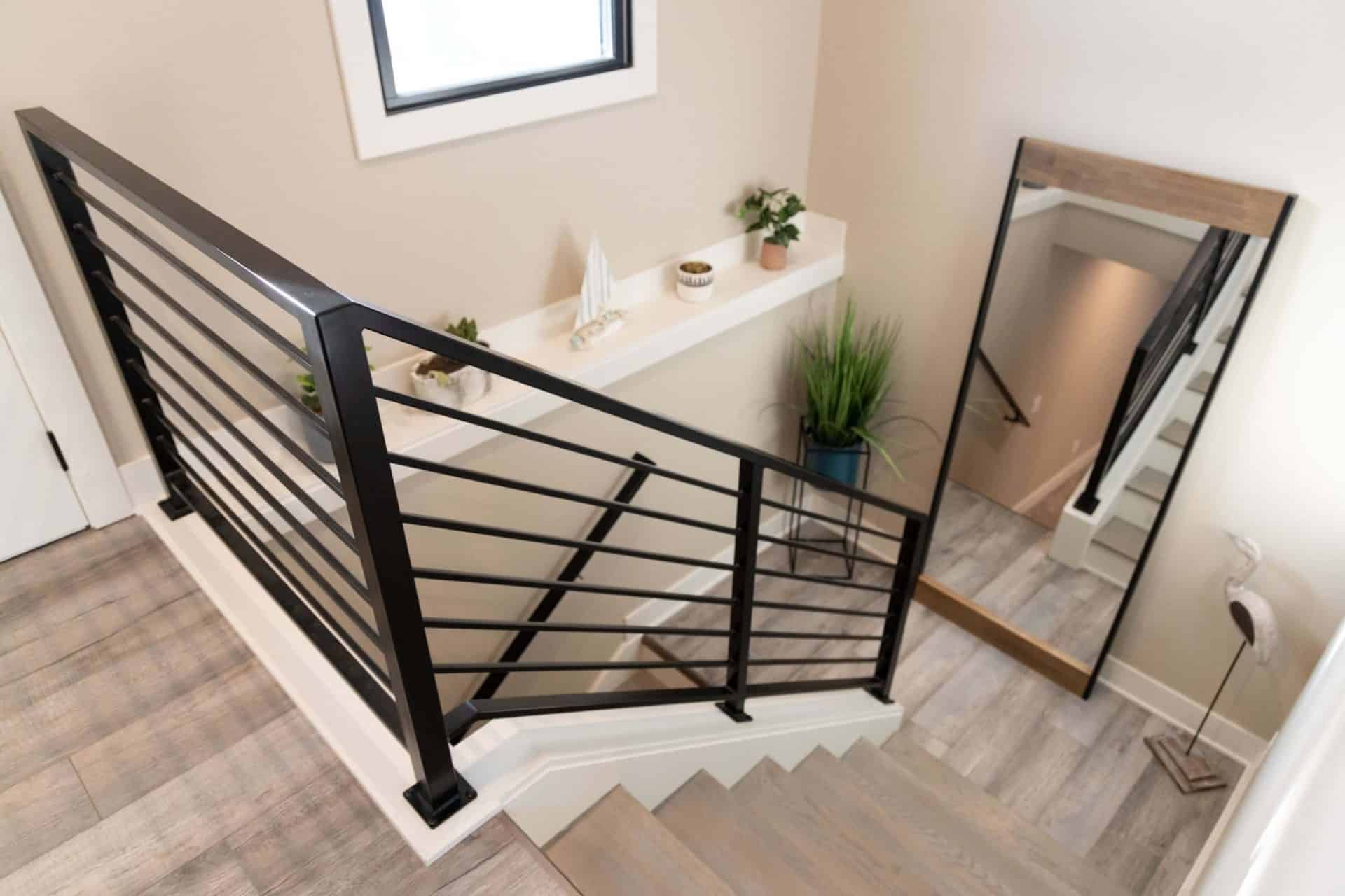 Modern staircase with black metal railing and wooden steps.