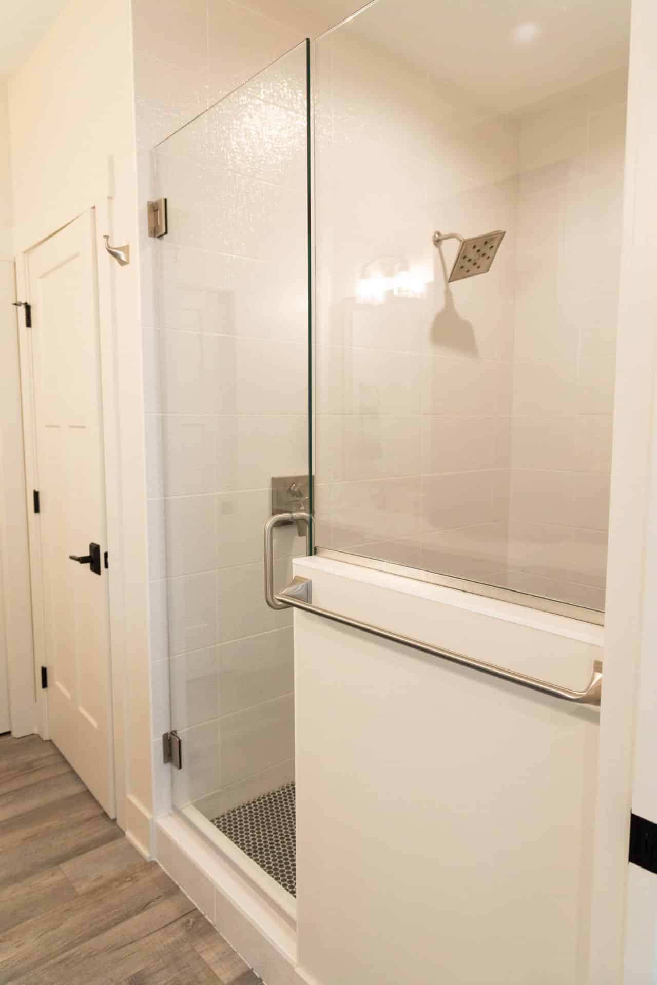 Modern walk-in shower featuring a sleek glass enclosure and a safety grab bar for accessibility.