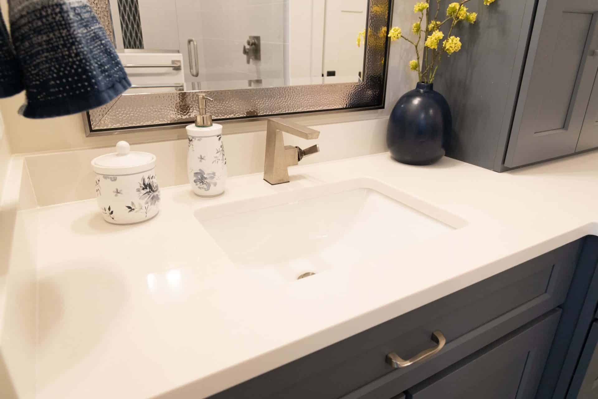 Modern bathroom vanity with navy cabinets and white countertop.