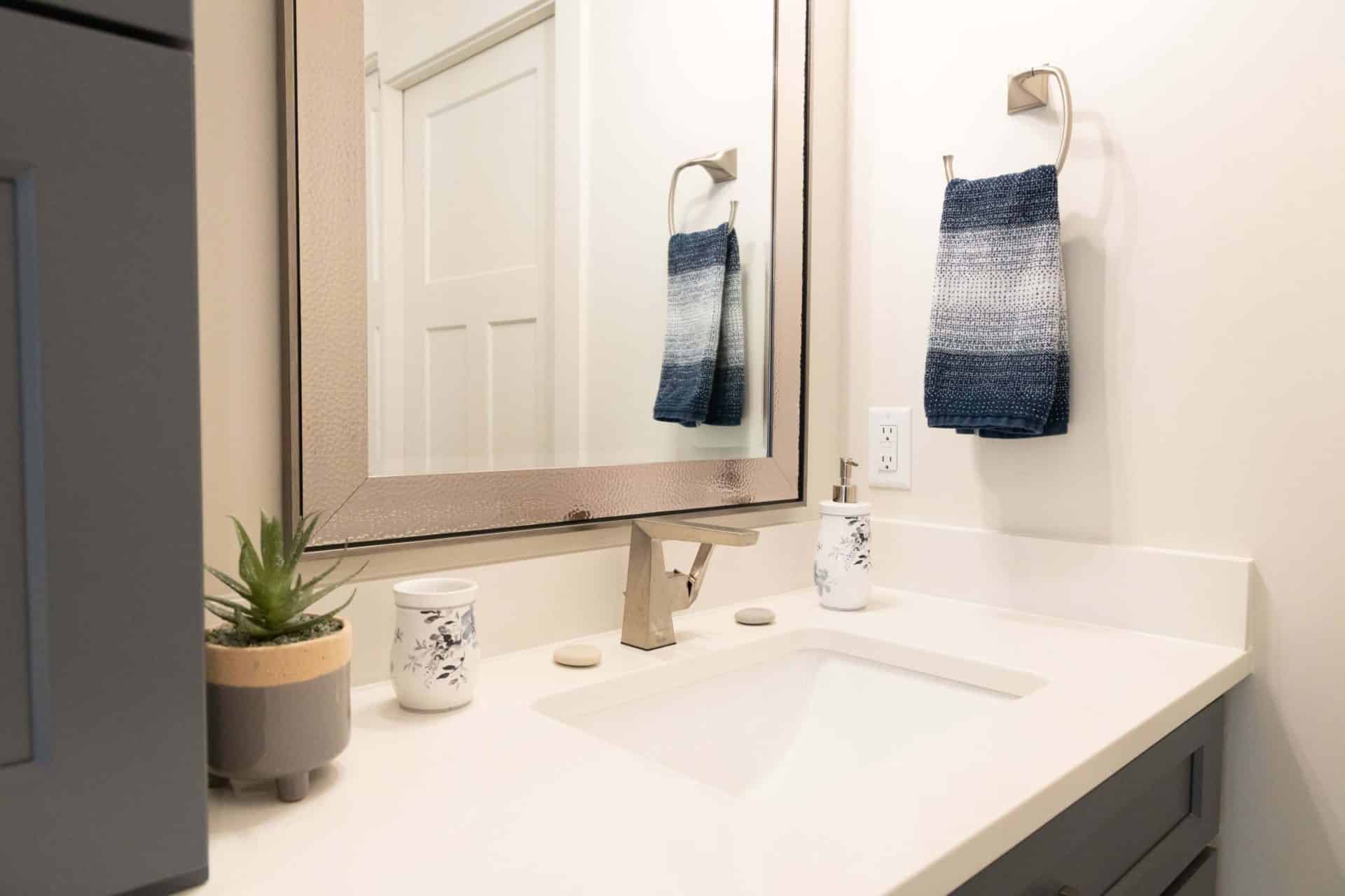 Modern bathroom vanity with mirror, towels, and decor in Livingston Homes.