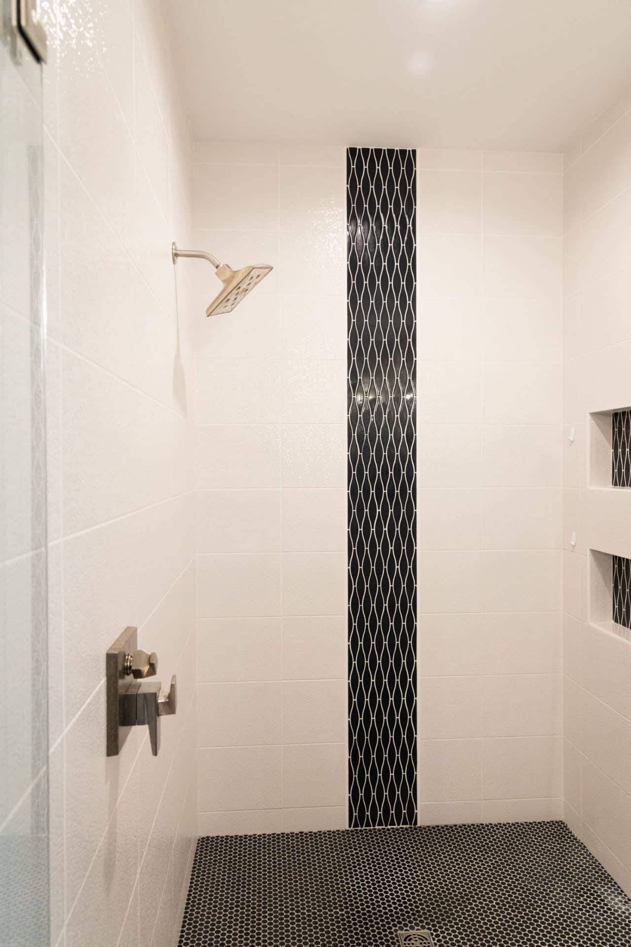 Elegant walk-in shower featuring a black tile accent strip and white tiled walls. Perfect for contem.