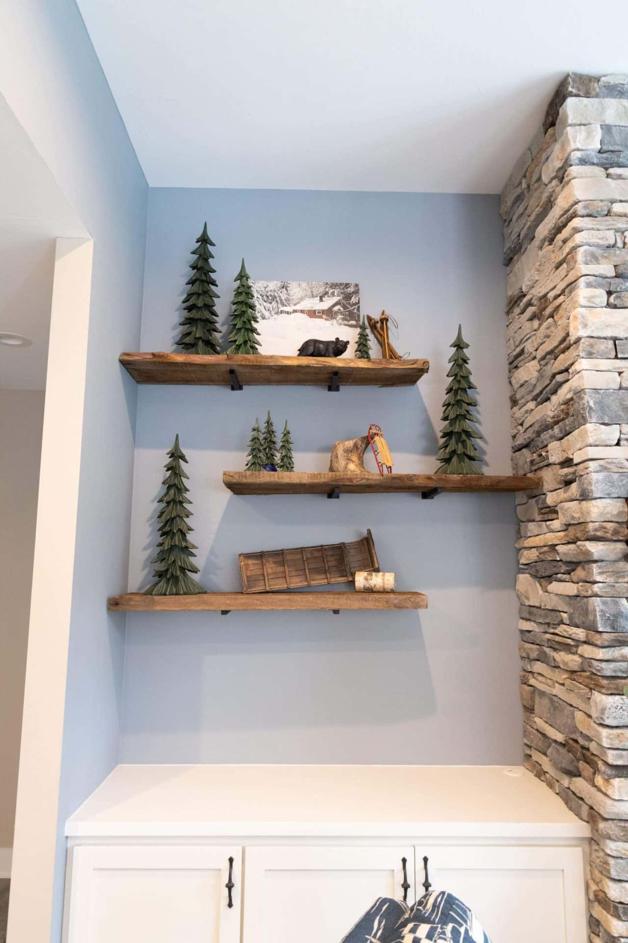 Cozy living room with wooden shelves decorated with miniature pine trees and rustic ornaments.