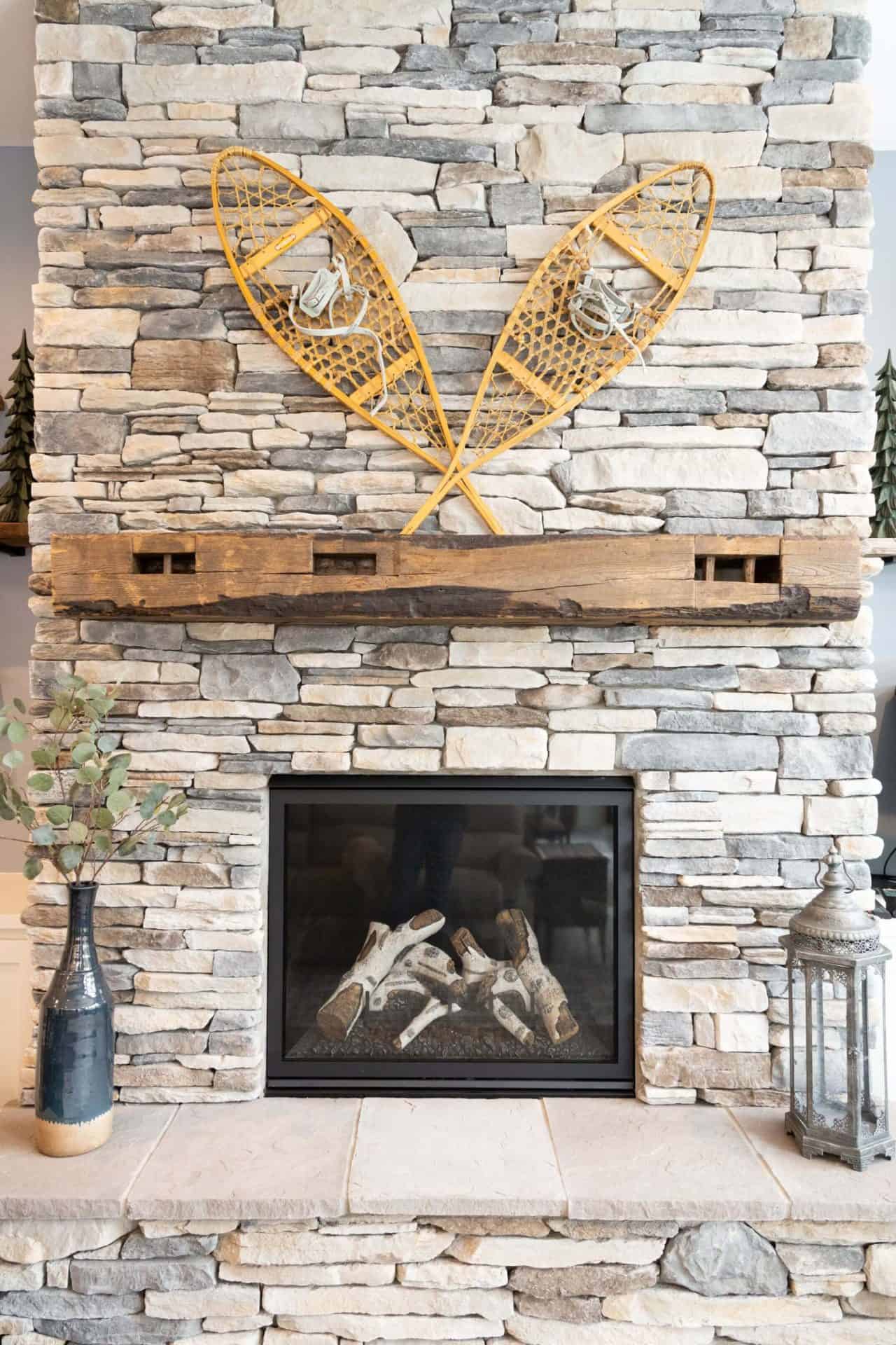 Cozy living room fireplace featuring decorative snowshoes mounted on a stone wall. Perfect for winte.