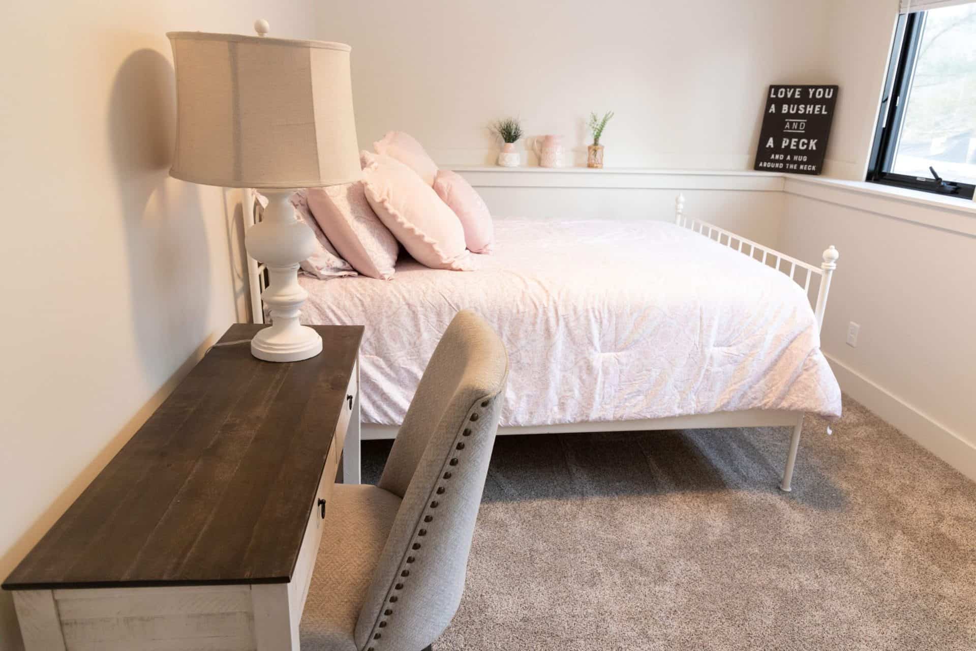 Cozy bedroom with white bed, beige pillows, and modern decor.