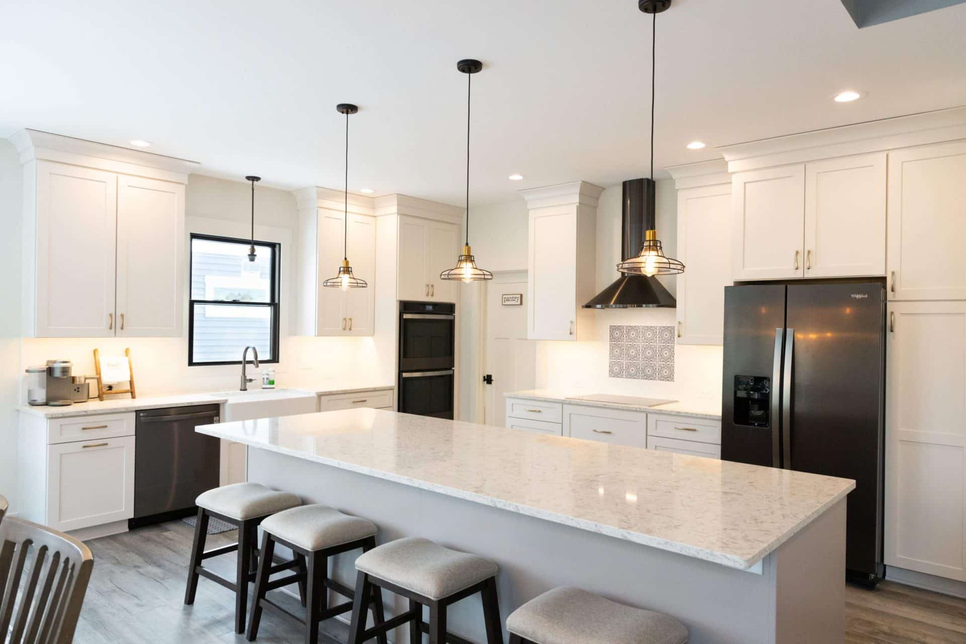 Modern white kitchen with island, pendant lighting, and stainless steel appliances.