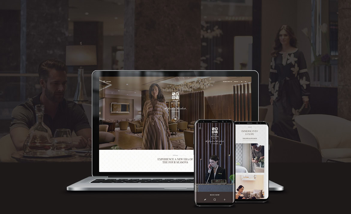 A laptop and smartphones displaying a website with a woman in a hotel room, with a man sitting nearby.