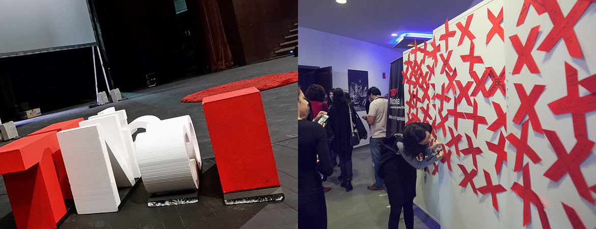Exhibition space with red and white geometric sculptures on the floor and a wall with red X patterns.