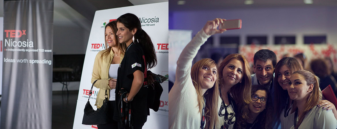 A group of people taking a selfie at a TEDx event with a TEDx Nicosia banner in the background.