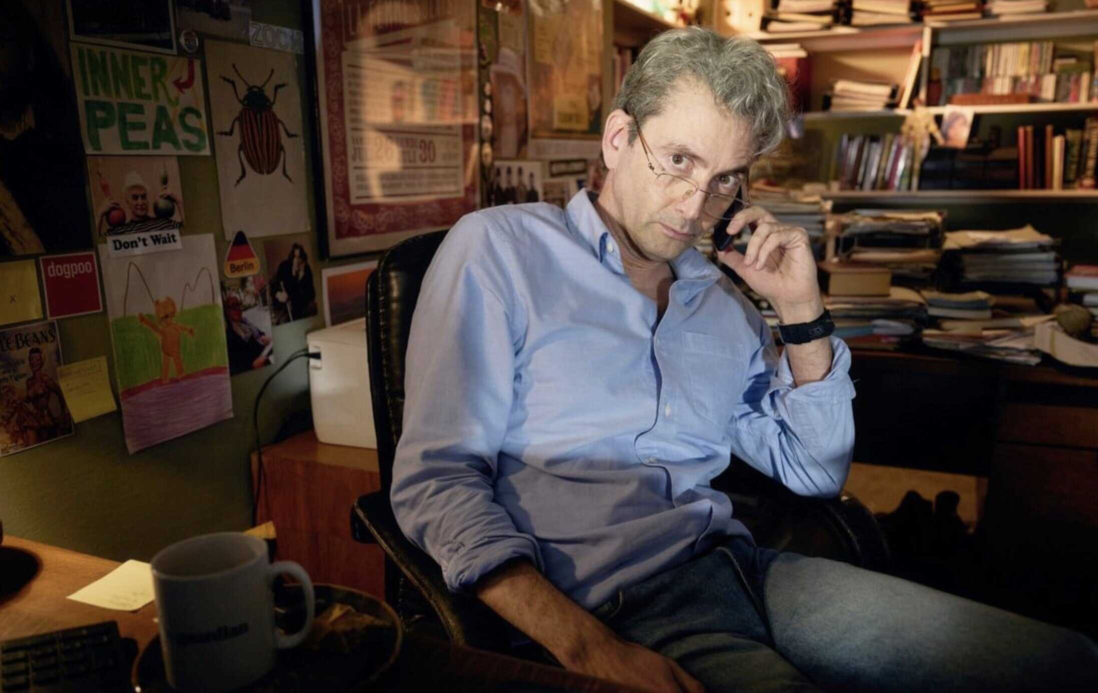 Blandad bild av man i arbetsrum med böcker och affischer, professionell miljö, bokhylla, kontor, inredning, arbetsplats, studiorum, arbetsmaterial, arbetsmiljö, kontorsarbete.