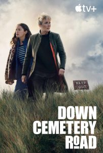 Bilden visar två kvinnor i en hög gräsmiljö med molnig himmel och en "Keep Out" skylt i bakgrunden – en actionfylld scen från serien "Down Cemetery Road" på Apple TV+ med fokus på spänning och mysterium.