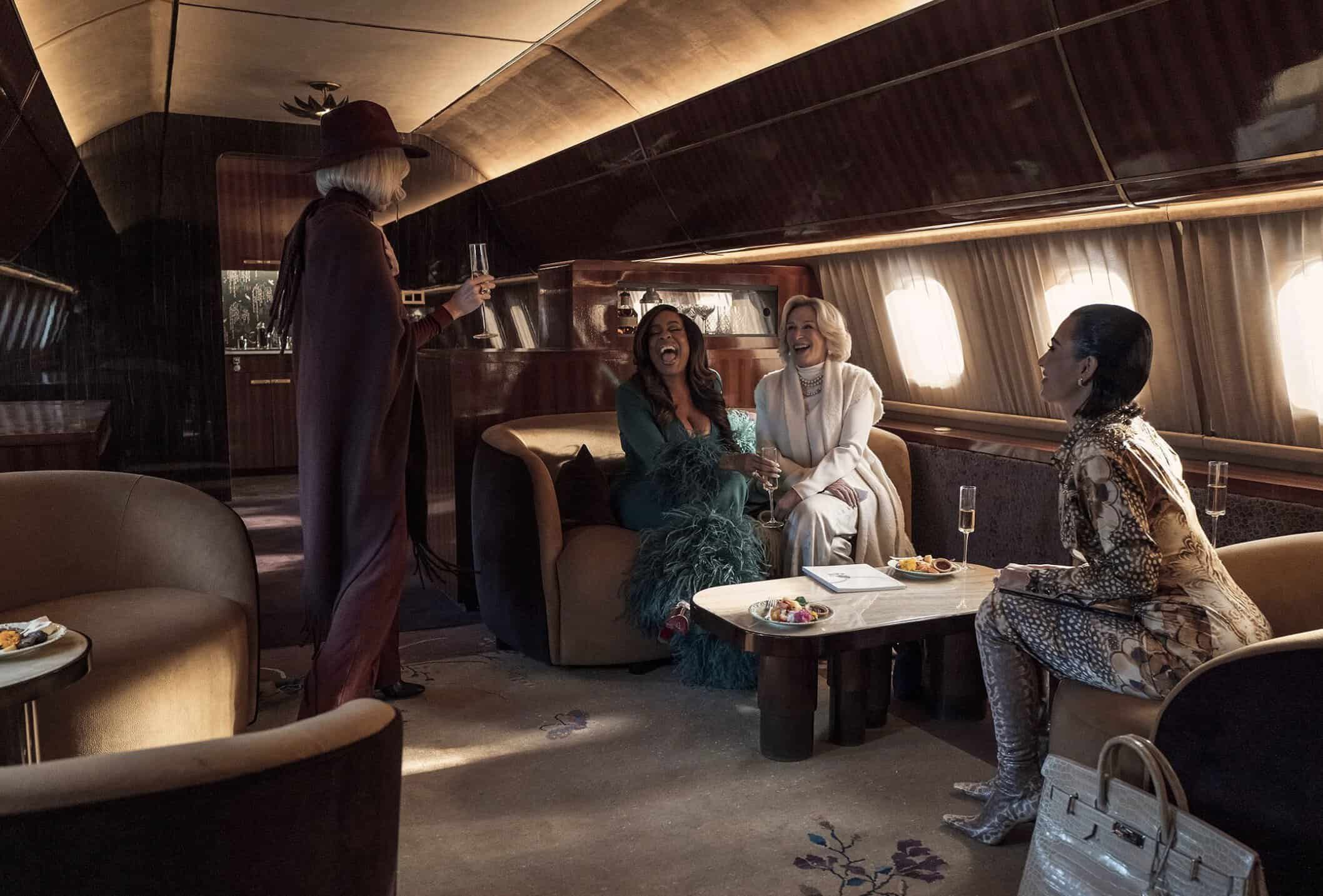 Ljus, lyxig lounge med glamorösa kvinnor som skrattar och dricker champagne, moderna inredningsdetaljer, exklusivt miljö, elegant och stilfull atmosfär, högkvalitativ service, festlig stämning, socialt umgänge, fashionabelt, affärssammanhang, mode, lyxliv, kvinnor i trendiga kläder, exklusiv reseskildring, glamour, lyxupplevelse, exklusiv lounge i modern design.