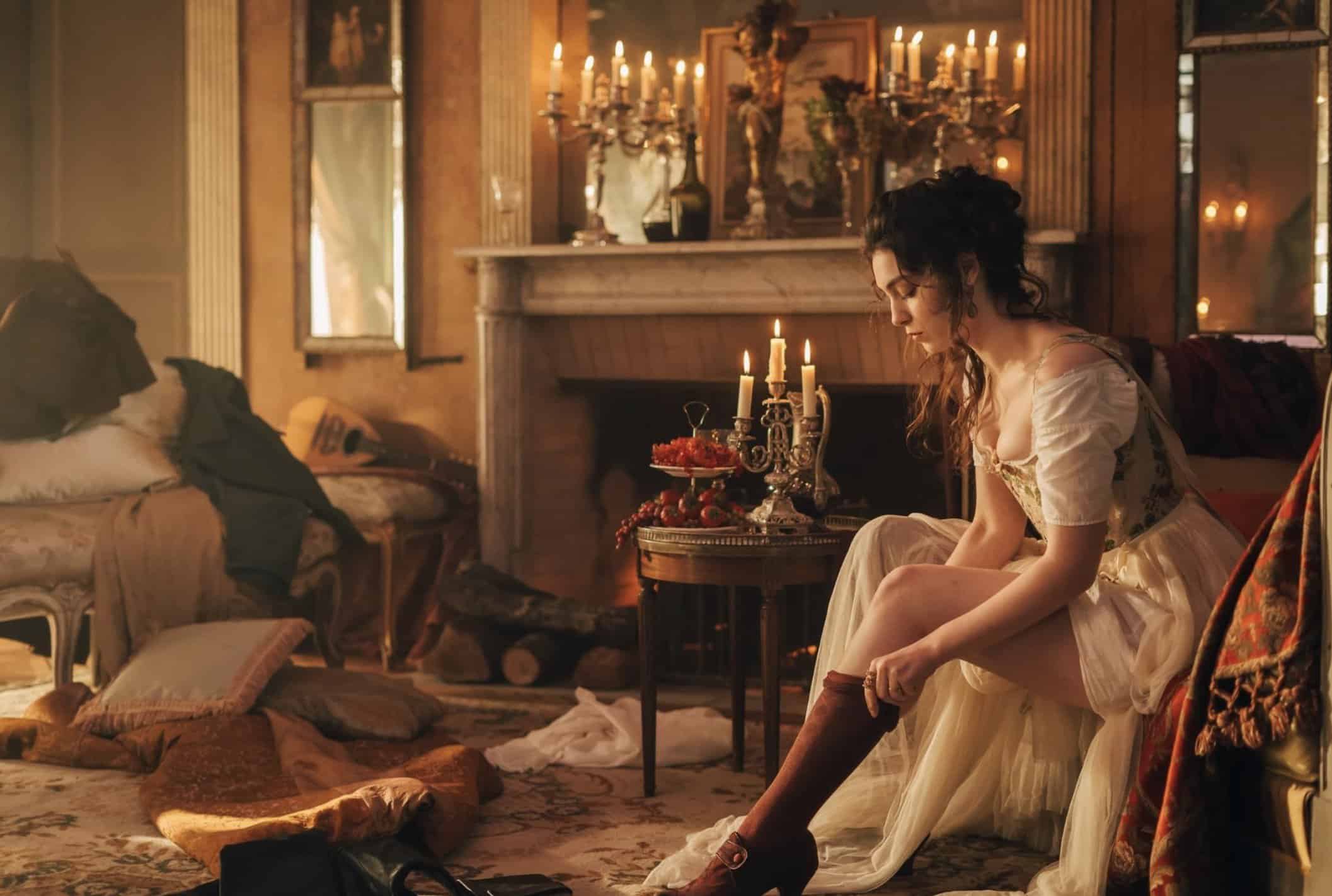 Detaljerad bild av ung kvinna i historisk klädsel som sätter på sig strumpor i ett elegant, gammaldags rum med levande ljus, för att skapa en varm, romantisk och klassisk atmosfär.