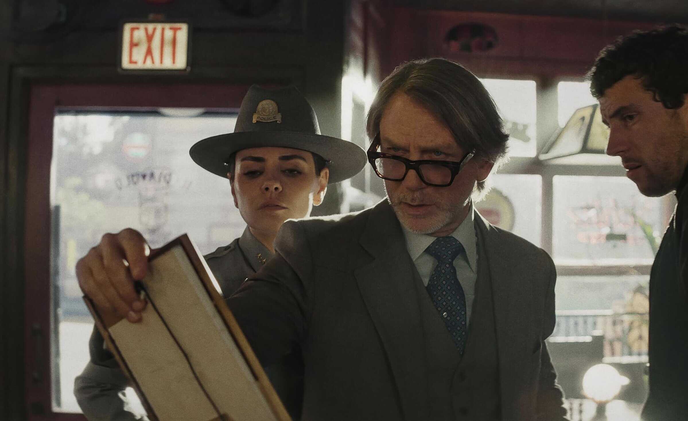 Svensk text: "Magasin MACKEN" i centrum, fokus på mode och klädsortiment. Fotografi av tre personer i butiksmiljö, en man med glasögon som kollar en katalog, en uniformerad kvinna och en man i mörk tröja.