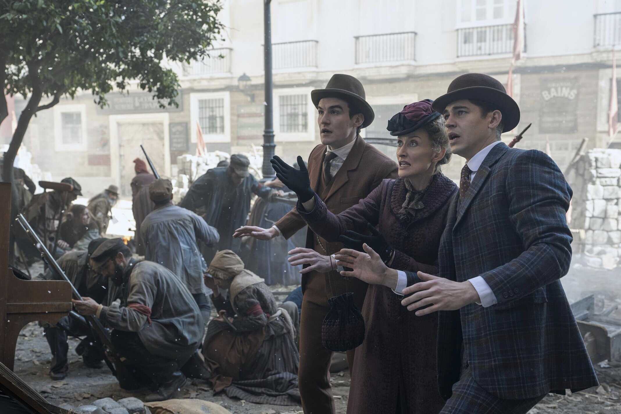 En bild av tre personer i tidstypiska kläder som gestikulerar under en historisk scen, med en bakgrund av andra människor och byggnader från en äldre stadsmiljö.