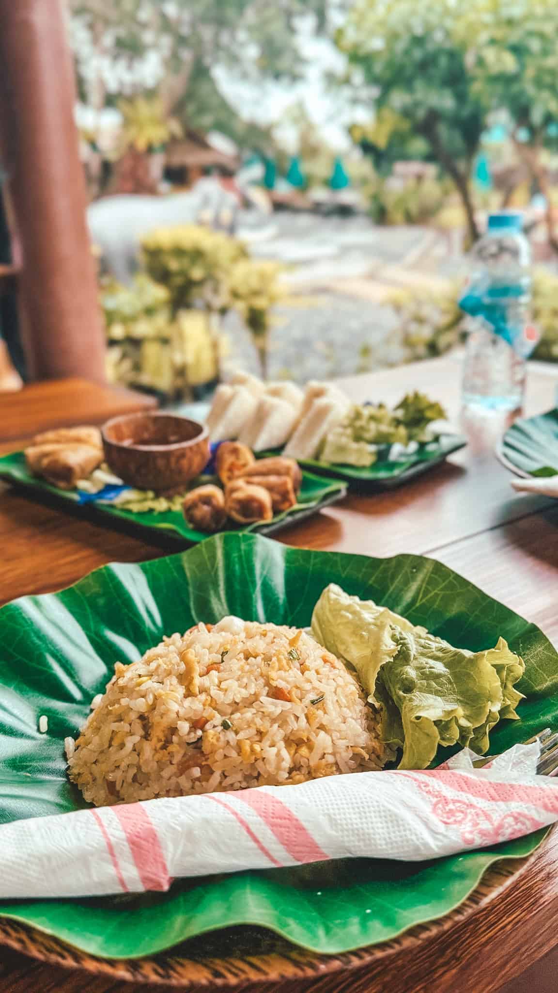 Traditional Thai meal with fried rice and fresh vegetables on a tropical outdoor table.