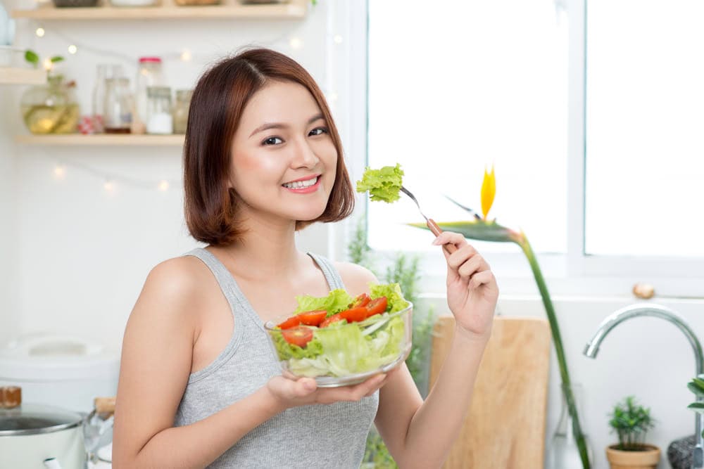 A woman is eating vegetables to nourish and strengthen her hair roots