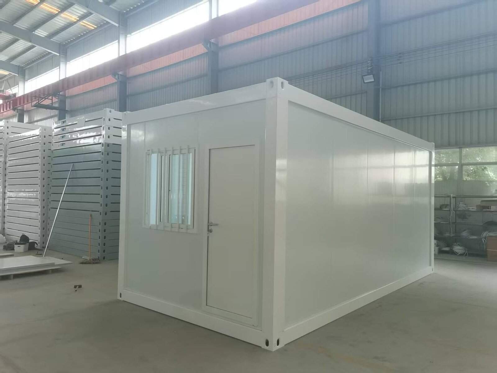 High-quality white modular prefabricated container unit inside a spacious industrial warehouse, showcasing customizable modular building solutions and efficient construction ready for assembly or deployment.