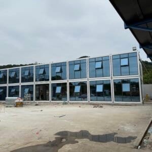 Modern modular prefab building with glass exterior, assembled on-site, offering customizable and sustainable housing solutions, perfect for residential and commercial use.