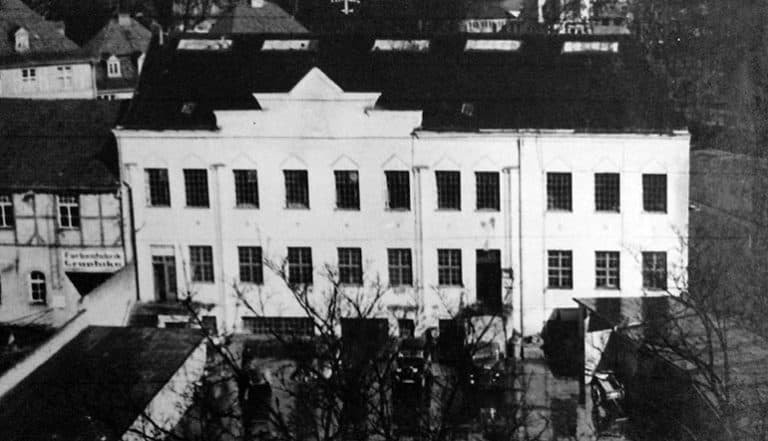 Altes, mehrstöckiges Gebäude in Trier mit Bäumen davor.