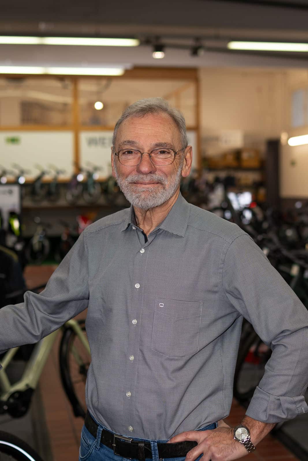 3 - 260128_shotitt-Monz-Fahrradwelten-Portraits-03_Dr.Heribert Monz Erfahrener Mann in Fahrradgeschäft mit Fahrrädern im Hintergrund.