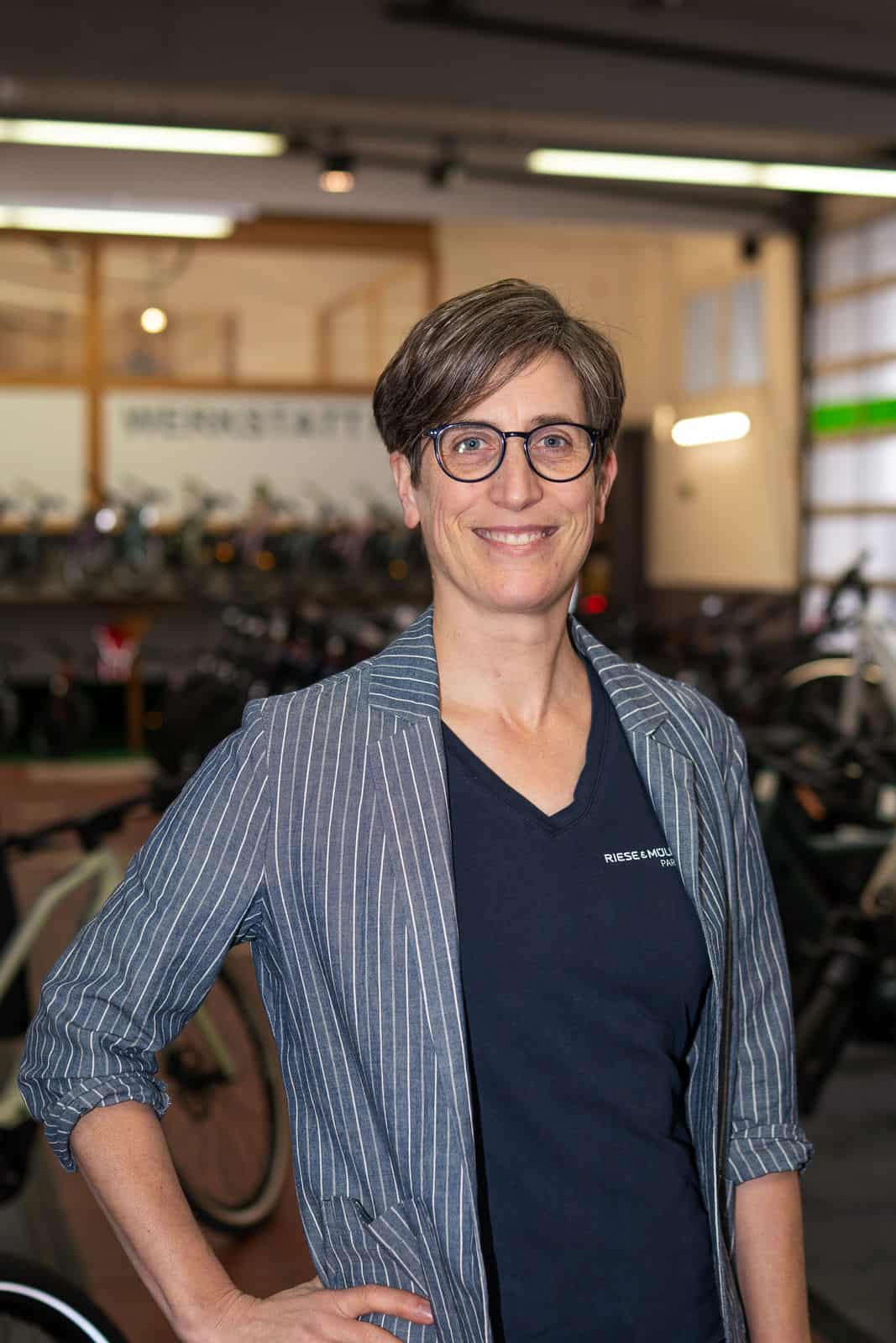 4 - 260128_shotitt-Monz-Fahrradwelten-Portraits-04_Kerstin Kolodzie Frau mit Brille und blauer Jacke in Fahrradgeschäft.