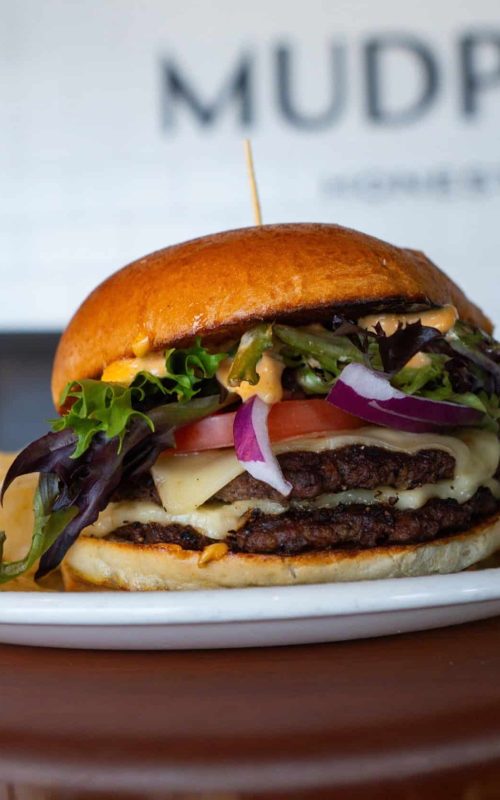 Delicious gourmet burger with fresh vegetables and melted cheese.