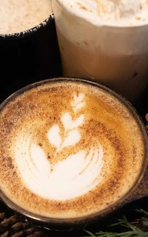 Latte with leaf-shaped foam art in a black cup.
