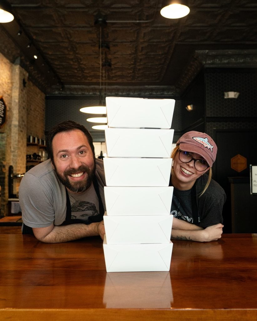 Pizza boxes stacked high with happy customers.