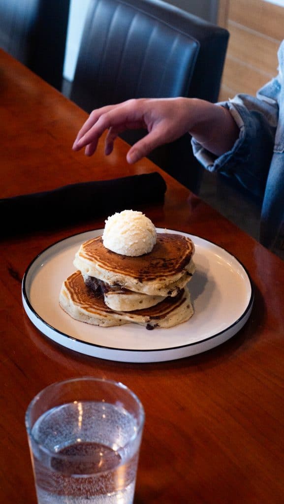 Delicious stack of homemade pancakes topped with coconut and syrup.