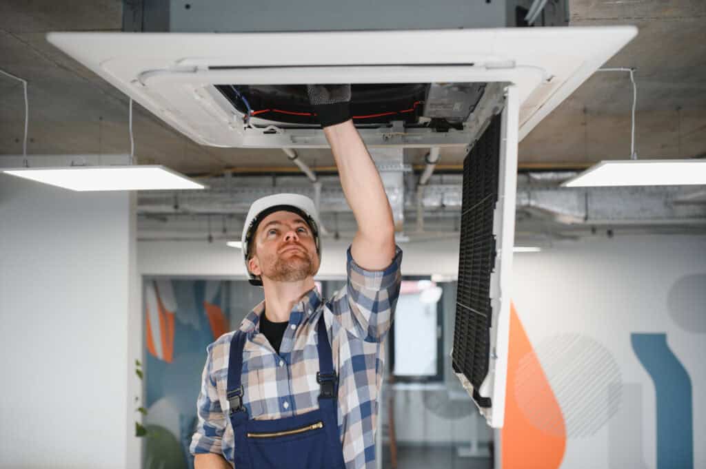 HVAC TECHNICIAN REPAIRING CEILING AIR CONDITIONING UNIT, TOP-RATED HVAC AND PLUMBING SERVICE, PROFESSIONAL INDOOR CLIMATE CONTROL, EXPERT HVAC REPAIR SERVICE, RELIABLE HEATING AND COOLING SOLUTIONS.