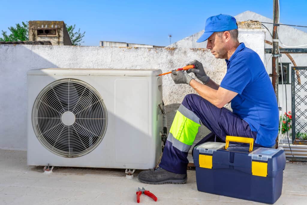 EFFICIENT HVAC TECHNICIAN PERFORMING MAINTENANCE ON AN OUTDOOR AIR CONDITIONING UNIT, EMPHASIZING PROFESSIONAL HEATING, VENTILATION, AIR CONDITIONING, AND PLUMBING SERVICES.