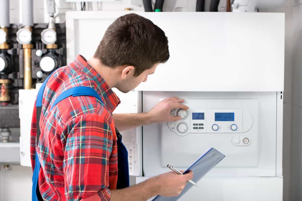 RELIABLE HVAC AND PLUMBING TECHNICIAN INSPECTING A BOILER WITH A CLIPBOARD IN A PROFESSIONAL HOME SERVICE SETTING.