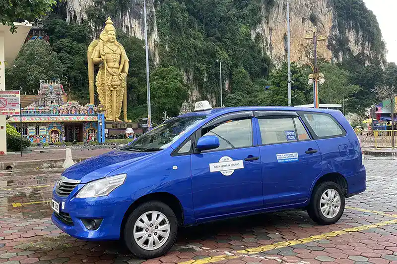 The Ultimate Guide To The 10 Best Day Trips from Kuala Lumpur (Local Expert Edition) 3 Blue taxi parked at Batu Caves with the Lord Murugan statue and temple in the background.