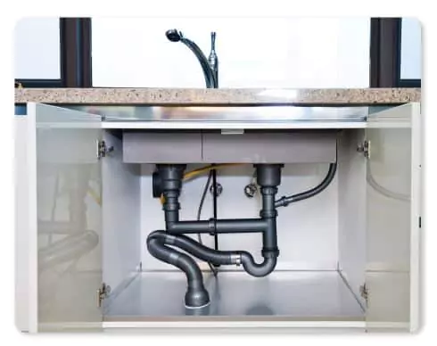 Pipes and plumbing under a kitchen sink with cabinet doors open, showing drainage and water supply lines—contact a professional for inspection or repairs.