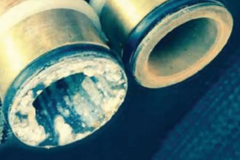 Close-up of two pipe fittings: one shows significant mineral buildup and corrosion from prolonged contact with water, while the other appears clean and clear.
