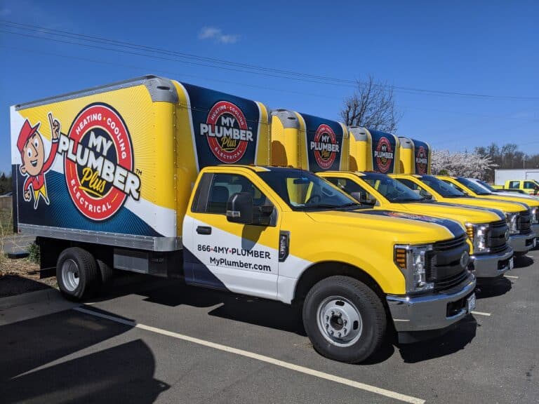 A row of yellow My Plumber Plus service trucks parked in a lot, featuring company branding and contact information on the side panels—ready to handle Plumbing Repair and Emergency Plumbing needs.