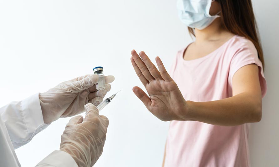 Child in pink shirt receiving vaccine from healthcare professional.
