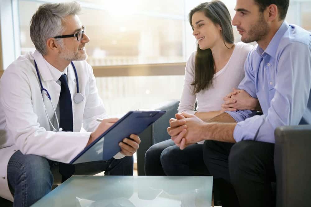 Doctor discussing IVF options with a couple in a clinic setting.