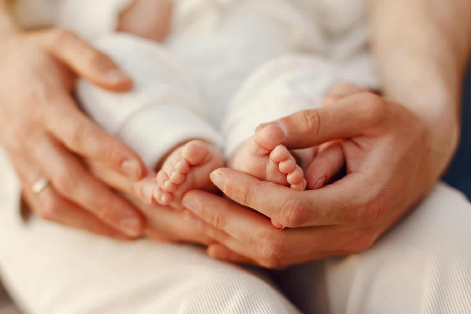 Close-up of newborn baby's feet held by parent.