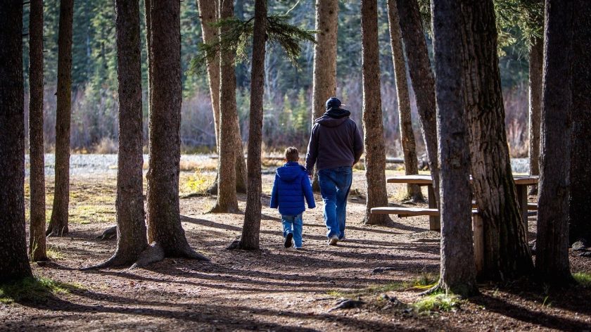Low budget uitjes voor kinderen - vader met kind wandelt in het bos