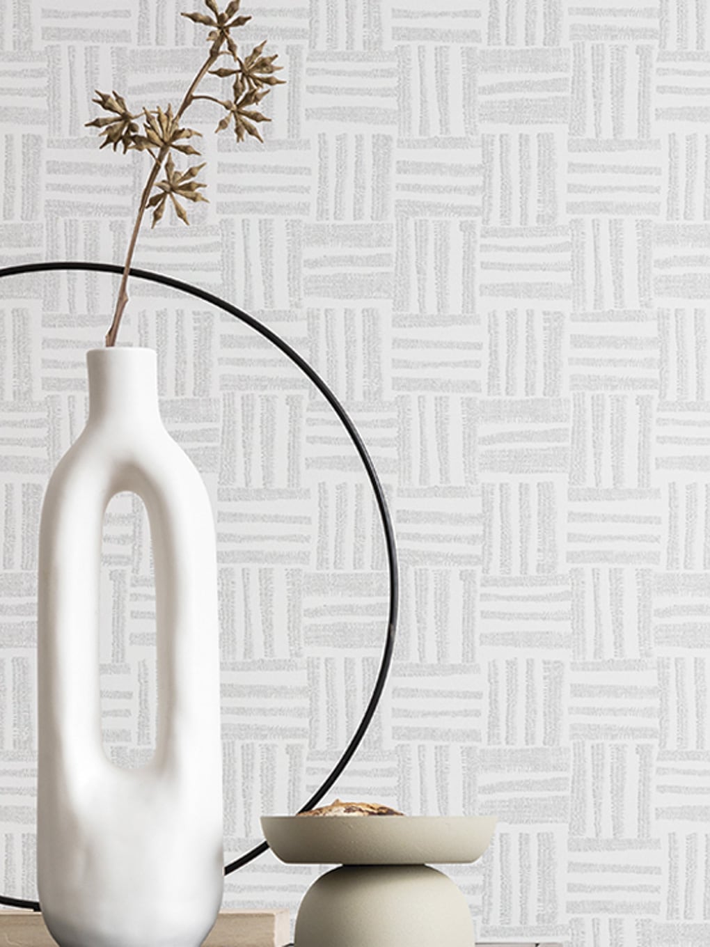 White ceramic vase with dried plant on a modern table against a textured geometric wallpaper backgro.