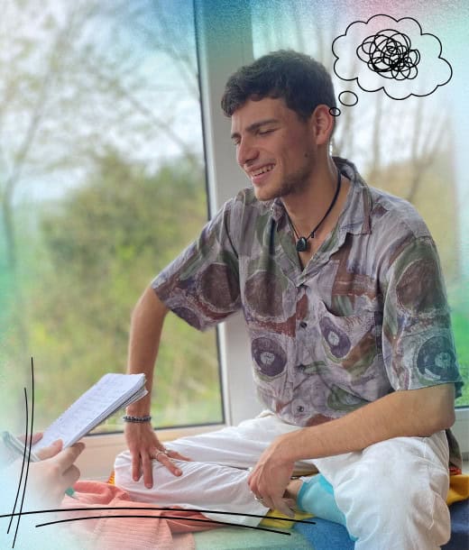 Ein Mann sitzt im Schneidersitz in einem Haus, lächelt mit geschlossenen Augen, während jemand einen Notizblock in der Hand hält; über seinem Kopf erscheint eine Gedankenblase mit einem Gekritzel.