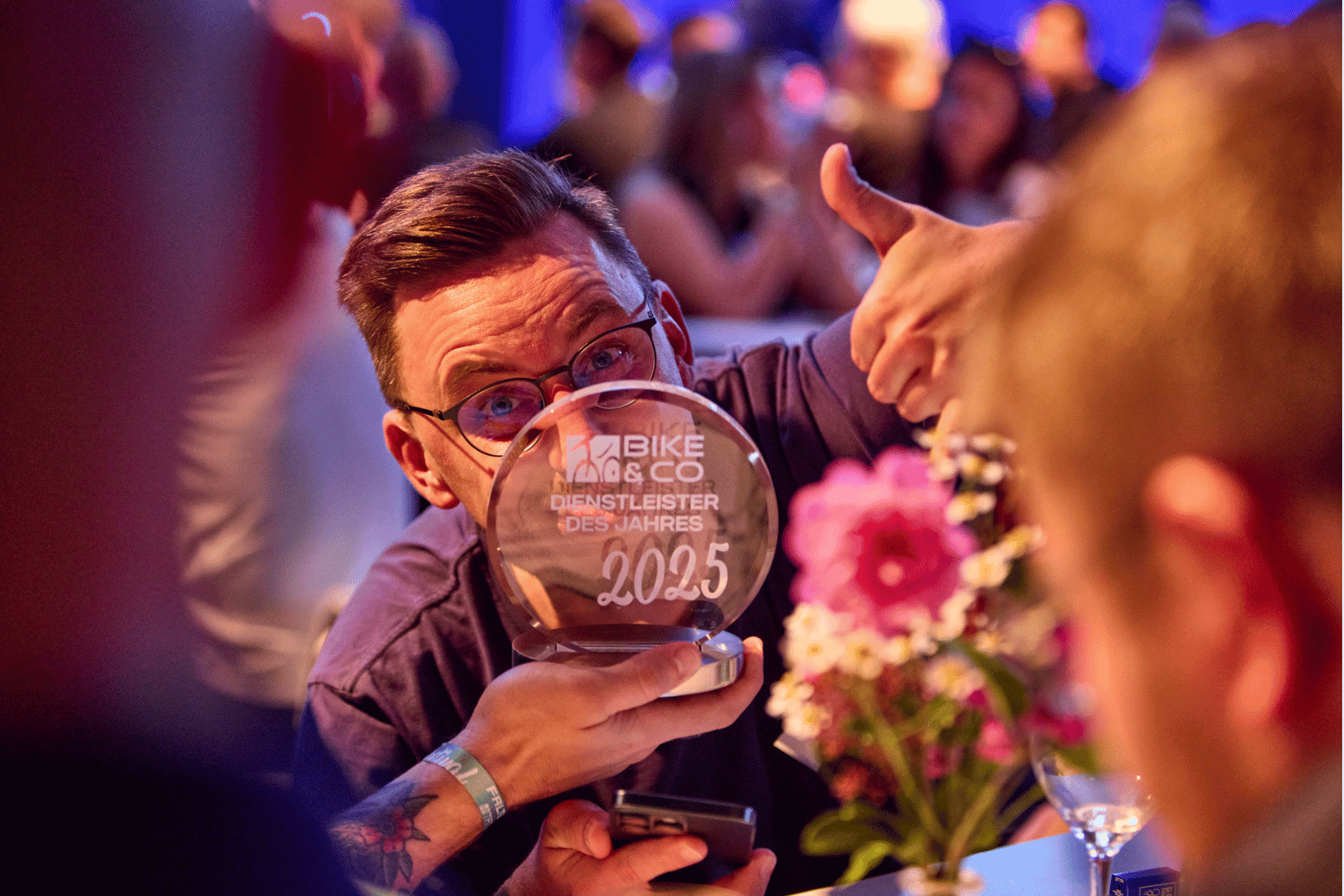 Mann hält Pokal mit 'Bike des Jahres 2025' bei Feier.