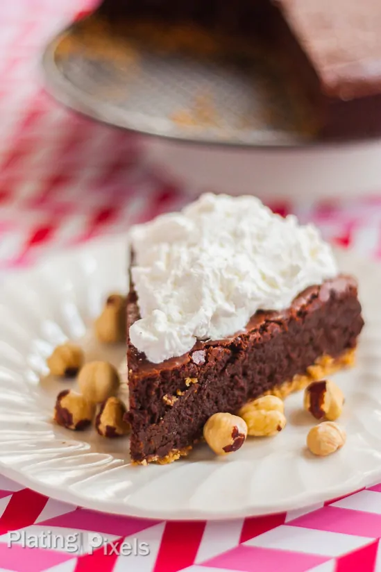 Chocolate Hazelnut Fudge Cake on a white plate with hazelnuts