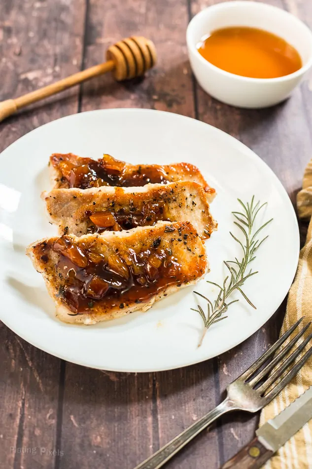 Honey Apricot Pork Chops on a white plate with the sauce in the background
