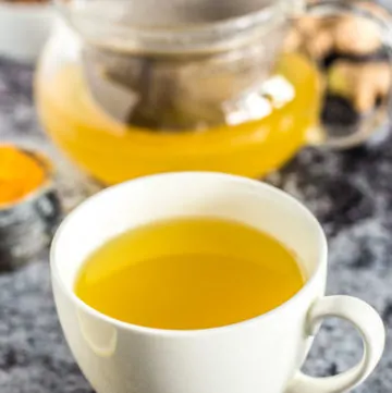 Cup of Turmeric Tea next to pot of more tea