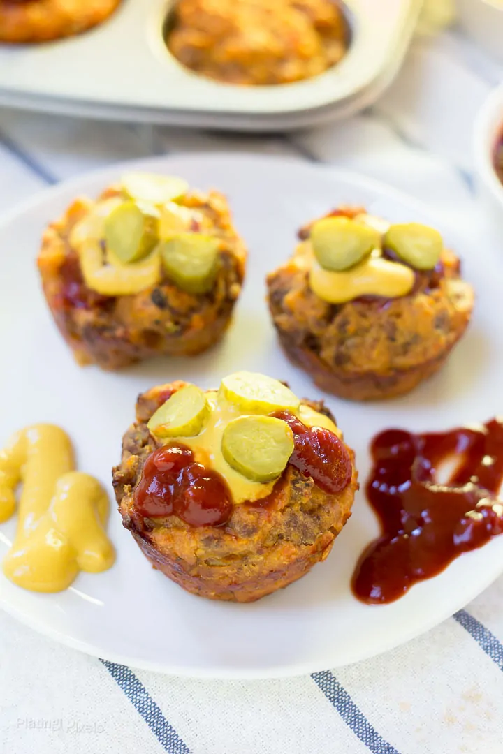 Mini Cheeseburger Muffins on a plate with pickles and ketchup